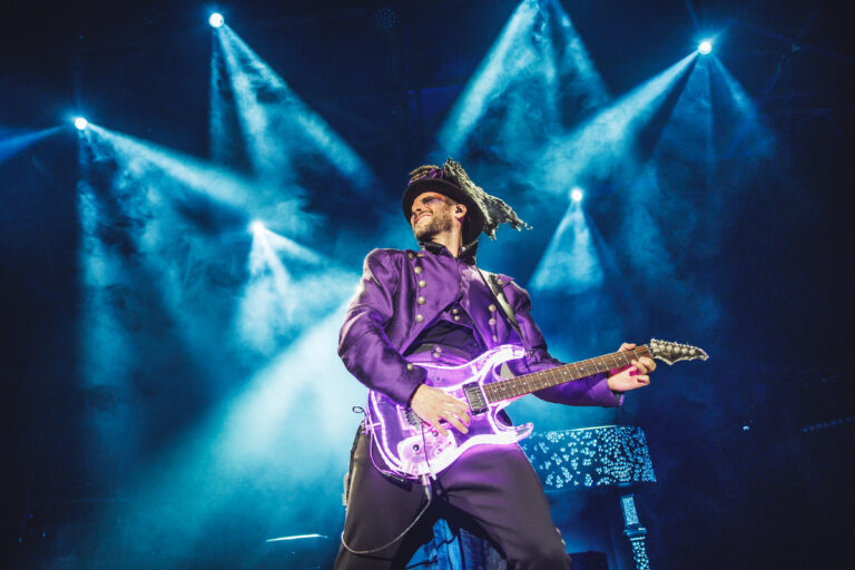 Guitarrista tocando bajo luces azules y guitarra eléctrica iluminada